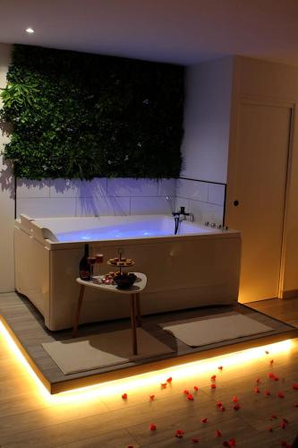La salle de bains est pourvue d'une baignoire avec une plante sur le mur. dans l'établissement L'Alchimie, à Salasc