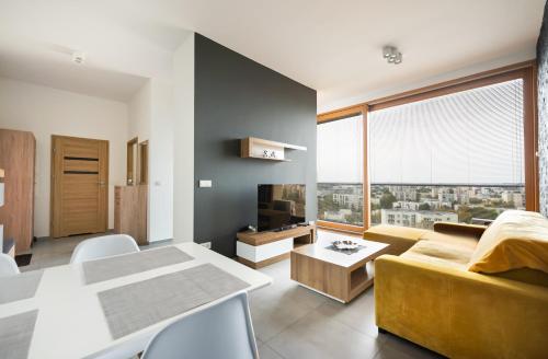 a living room with a yellow couch and a table at Metro Imielin 13th Floor Apartment by BookingHost in Warsaw