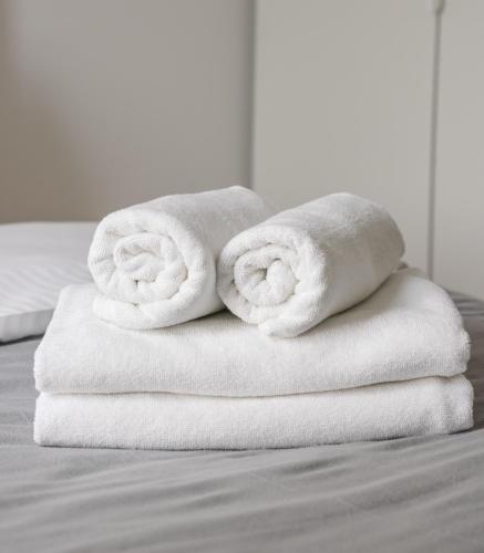 two towels are stacked on top of a bed at Metro Imielin 13th Floor Apartment by BookingHost in Warsaw