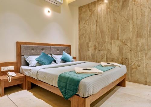 een slaapkamer met een groot bed met blauwe kussens bij Hotel Swamini Kolhapur in Kolhapur