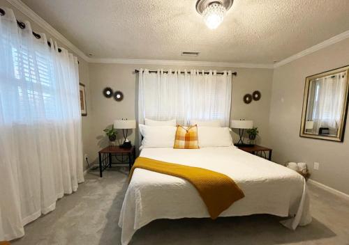 a bedroom with a bed with a yellow blanket on it at RusticParaiso: Family, Team & Group Urban Retreat in Greensboro