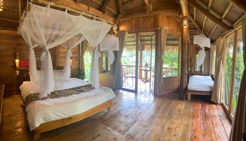 ein Schlafzimmer mit einem Himmelbett in einem Holzhaus in der Unterkunft Pu Luong Ecostay in Lũng Tiềm