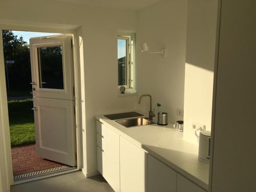 una cucina bianca con lavandino e specchio di Nije Haven Bed & Breakfast a Wrixum