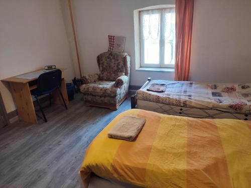 ein Schlafzimmer mit einem Bett, einem Stuhl und einem Schreibtisch in der Unterkunft Chambre Haut in Zilling