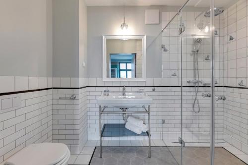 a white bathroom with a sink and a shower at Historical Townhouse by Blue Mandarin in Gdańsk