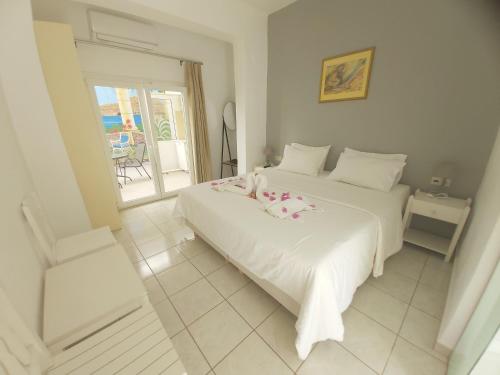 a bedroom with two white beds and a balcony at Antonios 1 in Matala