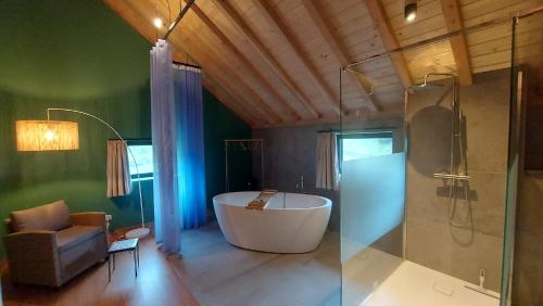 uma casa de banho com uma banheira, uma cadeira e um chuveiro em Chez Rosé em Sainte-Cécile