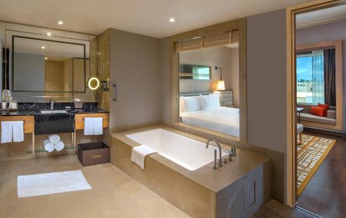 a bathroom with a tub and a bedroom with a bed at Welcomhotel by ITC Hotels, Bhubaneswar in Bhubaneshwar