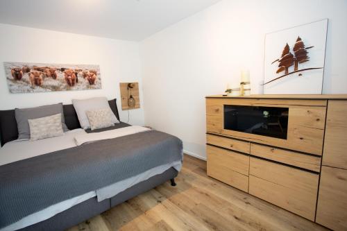 a bedroom with a bed and a dresser with a television at Ferienwohnung Albblick in Burladingen