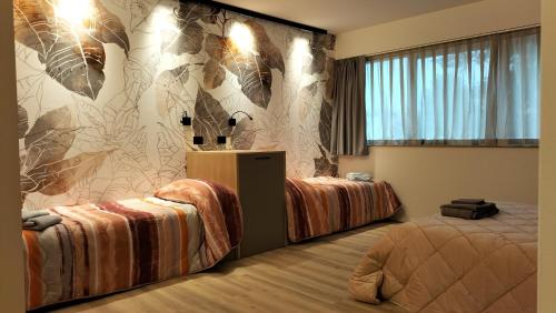 een slaapkamer met 2 bedden en een muur met bloemen bij fragilerooms in Dolo