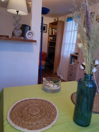 un vase vert avec des fleurs sur une table dans l'établissement HERM'S Petite maison atypique et cour privative -, à Cabourg