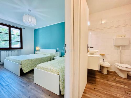 Duas camas num quarto com uma casa de banho e um lavatório. em Mercury Apartment - Vista Lago con Piscina em Sirmione