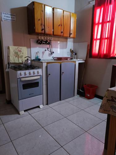 a kitchen with a stove and a sink and cabinets at Hostel el Amanecer in Puerto Iguazú