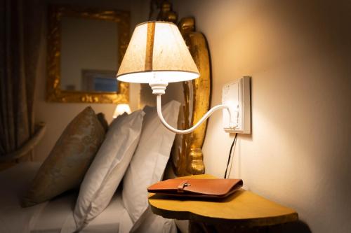 a lamp on a table next to a bed with pillows at San Giorgio Rooms in Genova