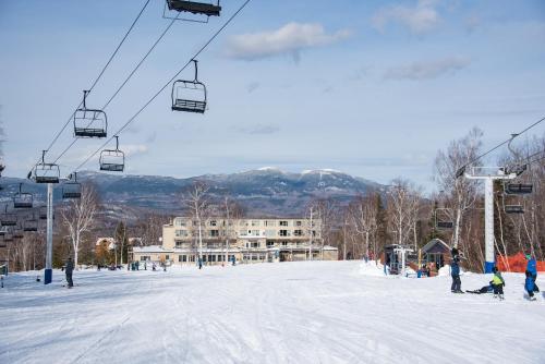a group of people on a ski lift in the snow at Sugarloaf Inn in Carrabassett