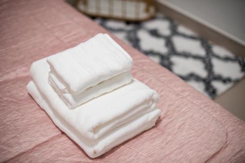 three white towels stacked on a pink bed at Betong 939Homestay in Betong