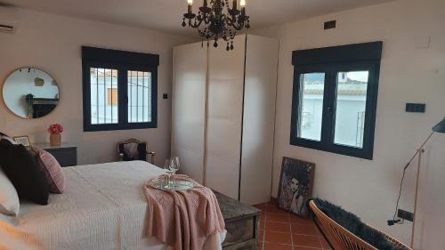 a bedroom with a bed with a table and two windows at CASA CUEVA A-TIPICA in Pegalajar