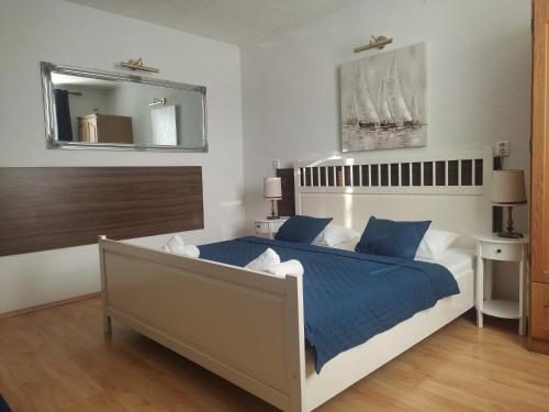 a bedroom with a bed with blue sheets and a mirror at Spa & Pool Apartment Hotel - Restaurant VILLA IVICA in Bratislava