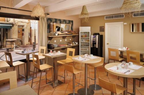 een restaurant met tafels en stoelen in een kamer bij The Originals Boutique, Hôtel Cassitel, Cassis in Cassis