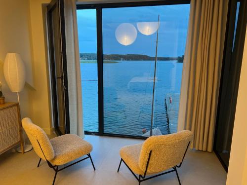 a room with two chairs and a view of the water at Pokój z widokiem na jezioro in Pluski