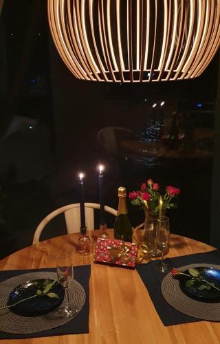 a wooden table with plates and glasses and a light at Pokój z widokiem na jezioro in Pluski