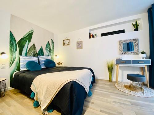 a bedroom with a bed with blue pillows and a desk at Appartement douillet avec terrasse in Talence