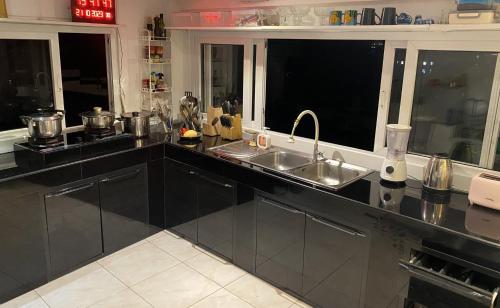 a kitchen with black cabinets and a sink and windows at OASIS VILLA Suites & Rooms in Karon Beach