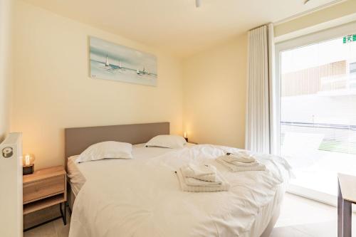een slaapkamer met een groot wit bed en handdoeken bij Sailorshouse in Nieuwpoort