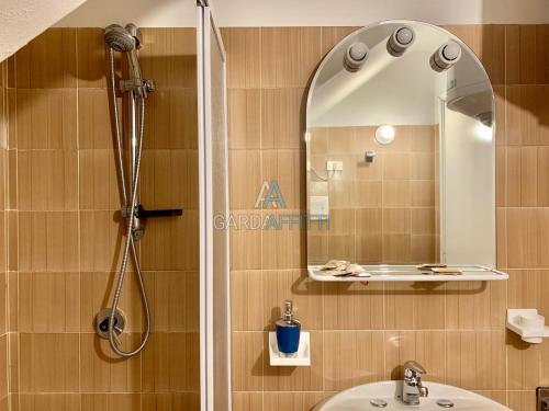 uma casa de banho com um chuveiro, um lavatório e um espelho. em Turchese Apartment - centrico e con piscina em Sirmione