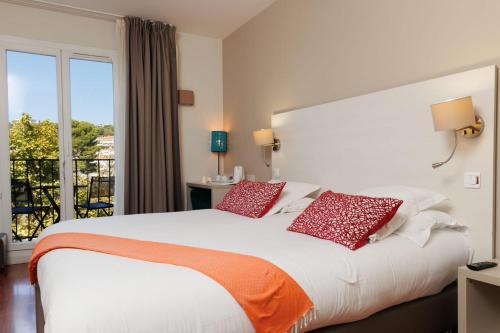 1 dormitorio con 1 cama blanca grande con almohadas rojas en The Originals Boutique, Hôtel Cassitel, Cassis, en Cassis