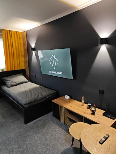 a room with a bed and a desk and a tv at Medyka Loft in Medyka