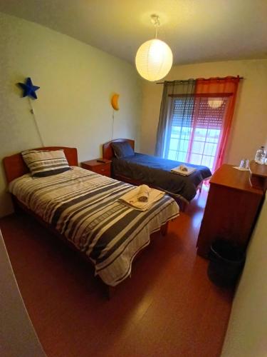 a bedroom with two beds and a table and a window at CASA DIAS in Vila do Bispo