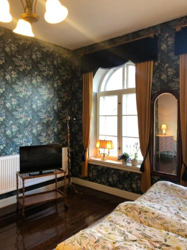 a bedroom with a bed and a mirror and a window at Cafebrumman in Neksø