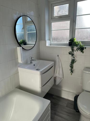 La salle de bains blanche est pourvue d'un lavabo et d'un miroir. dans l'établissement Kenton Apartment- Wembley links, à Harrow Weald