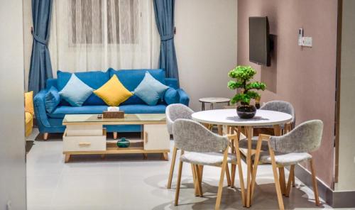 Una sala de estar con un sofá azul y una mesa y sillas. en شقق وغرف امار للشقق المخدومة حي الربيع فئة التصنيف اقتصادي, en Riad