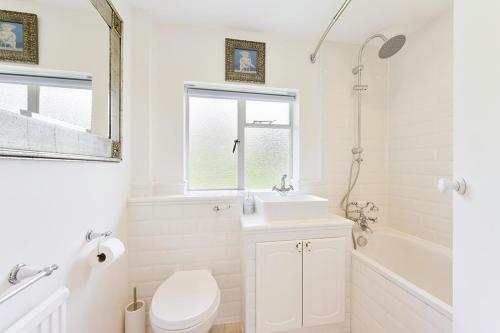 a white bathroom with a toilet and a sink at Pass the Keys Hidden Cottage in Esher, West End in Esher