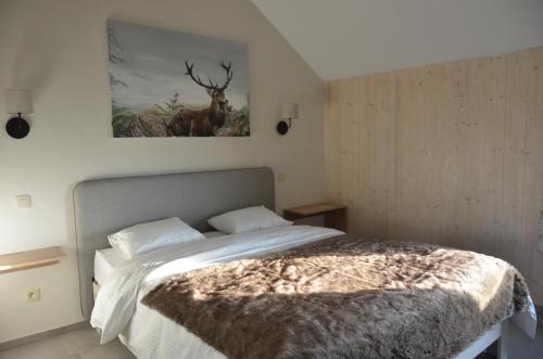 1 dormitorio con 1 cama con una foto de ciervo en la pared en La clef des bois, en Paliseul