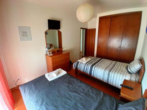 a bedroom with two beds and a dresser and a tv at CASA DIAS in Vila do Bispo
