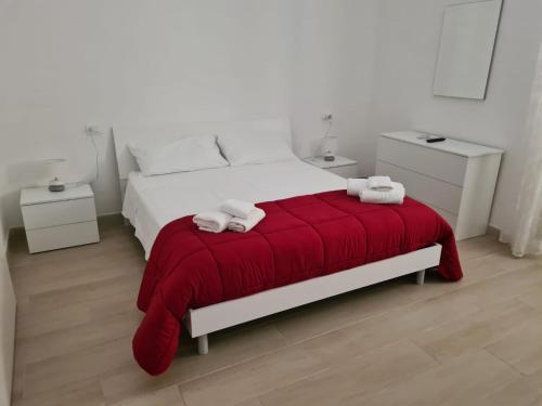 a bedroom with a white bed with a red blanket at Casa del papà in Noto