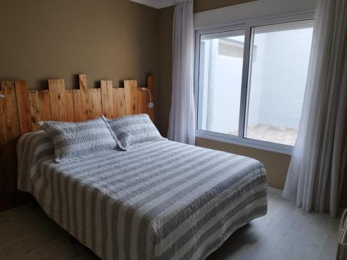 1 dormitorio con 1 cama con cabecero de madera y ventana en Rosana Mariel en 