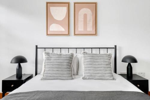 a bedroom with a bed with two lamps and two pictures on the wall at Exquisite 2 Bed Soho Central Apartment Sleeps 6 in London