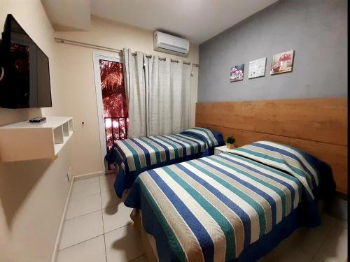 a room with two beds and a tv and a window at Beach Living - Porto das Dunas - Ap Terreo 200m Beach Park PÉ NA AREIA in Aquiraz