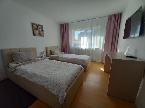 a hotel room with two beds and a television at 4 Seasons Apartments in Bistriţa