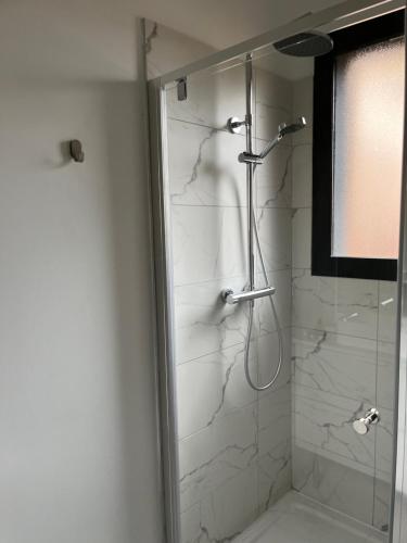 une salle de bain avec une douche avec une porte vitrée dans l'établissement Maison des landes st Julien en Born Contis, à Saint-Julien-en-Born