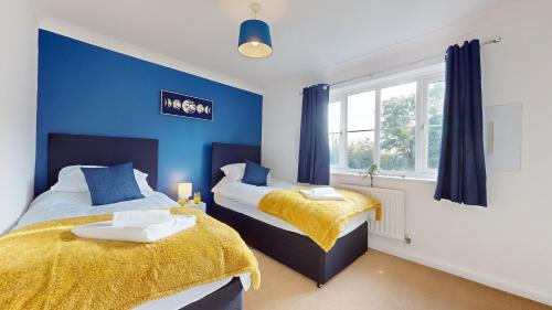 2 camas en una habitación con paredes azules en Duxford Deluxe 