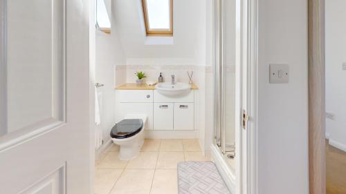 a white bathroom with a toilet and a sink at Duxford Deluxe 