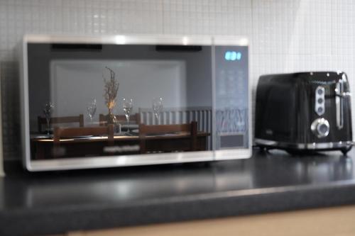 a microwave sitting on top of a counter with a toaster at Duxford Deluxe in Thriplow