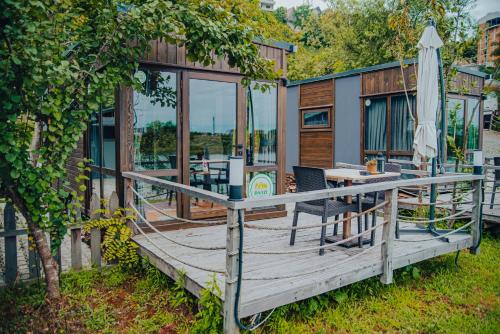 a house with a deck with a table and an umbrella at Danzi camping tiny house in Rize