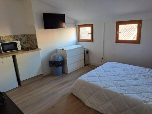 a bedroom with a bed and a kitchen with a microwave at 195, studette porte d'Italie rue populaire. in Toulon