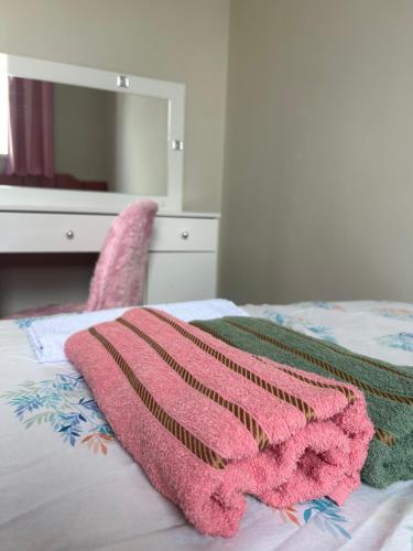 una manta rosa sentada encima de una cama en Apartamento ACOMODA 5 PESSOAS próximo ao Uberlândia Shopping en Uberlândia